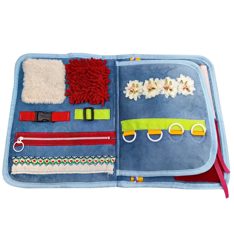 Open toy activity book with various textured and colorful elements on a white background