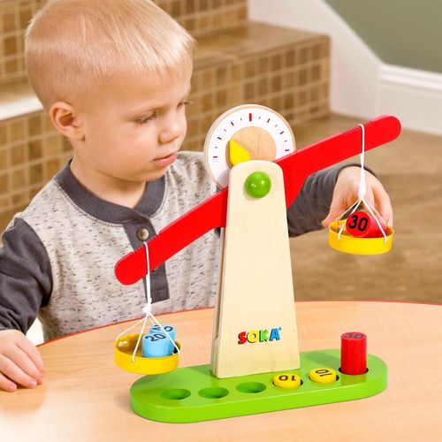 Child interacting with miniature weighing scale set to explore counting and tactile comparison