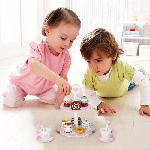 Child serving pretend cake slices from pastel cake stand to build social hosting routines