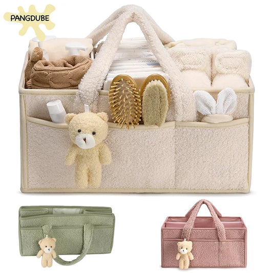 Soft felt nappy caddy organiser shown with compartments filled with baby essentials like nappies, wipes, and cream tubs on nursery table