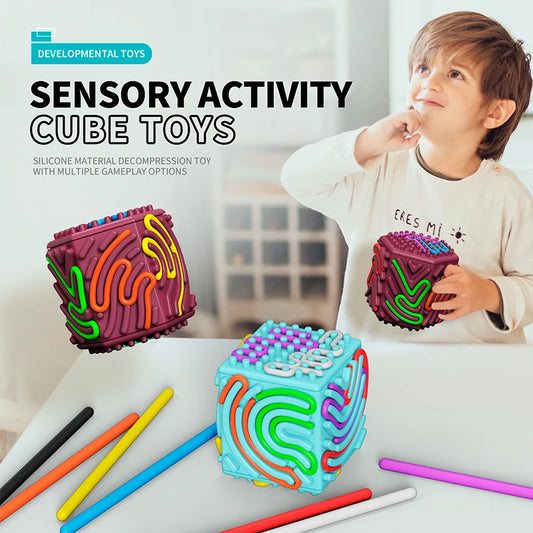 Sensory activity cube toys with colorful designs on a table, featuring a child playing with them.