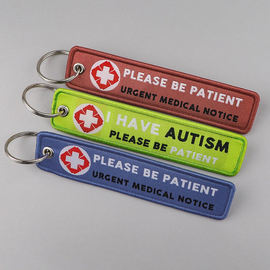 Three keychains with medical and autism awareness messages on a gray background