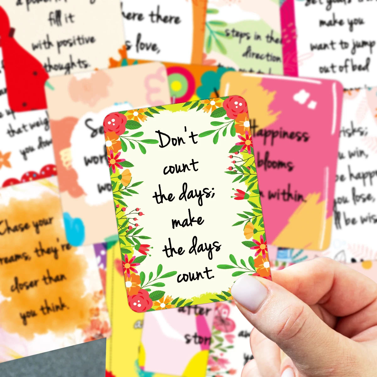 Colorful card with motivational quote held by a hand against a background of other cards.