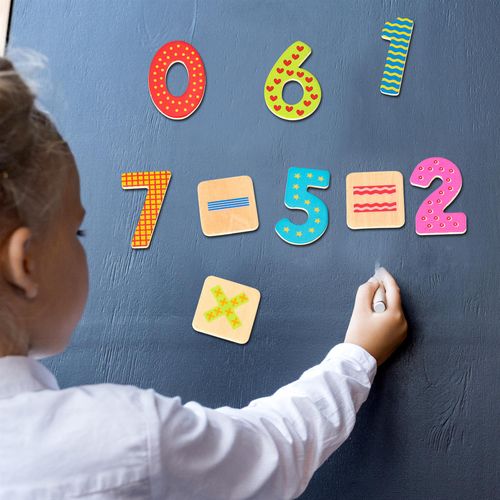Child arranging magnetic digits on whiteboard to practise equations and build number confidence