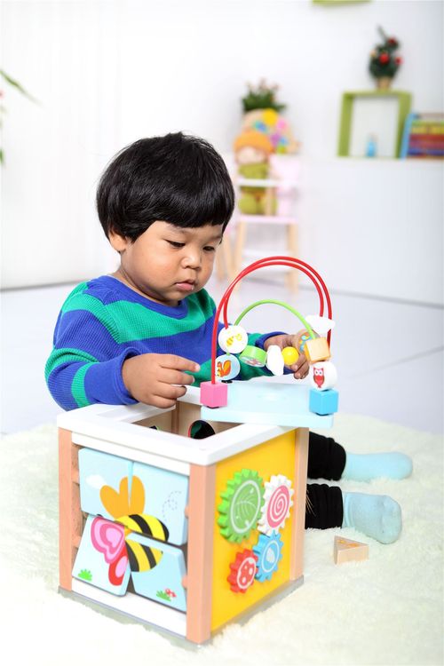Child engaging with multi-sided wooden cube to build hand–eye coordination and problem-solving