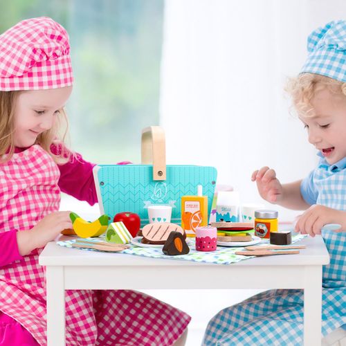 Two children playing with picnic toy set at a table.